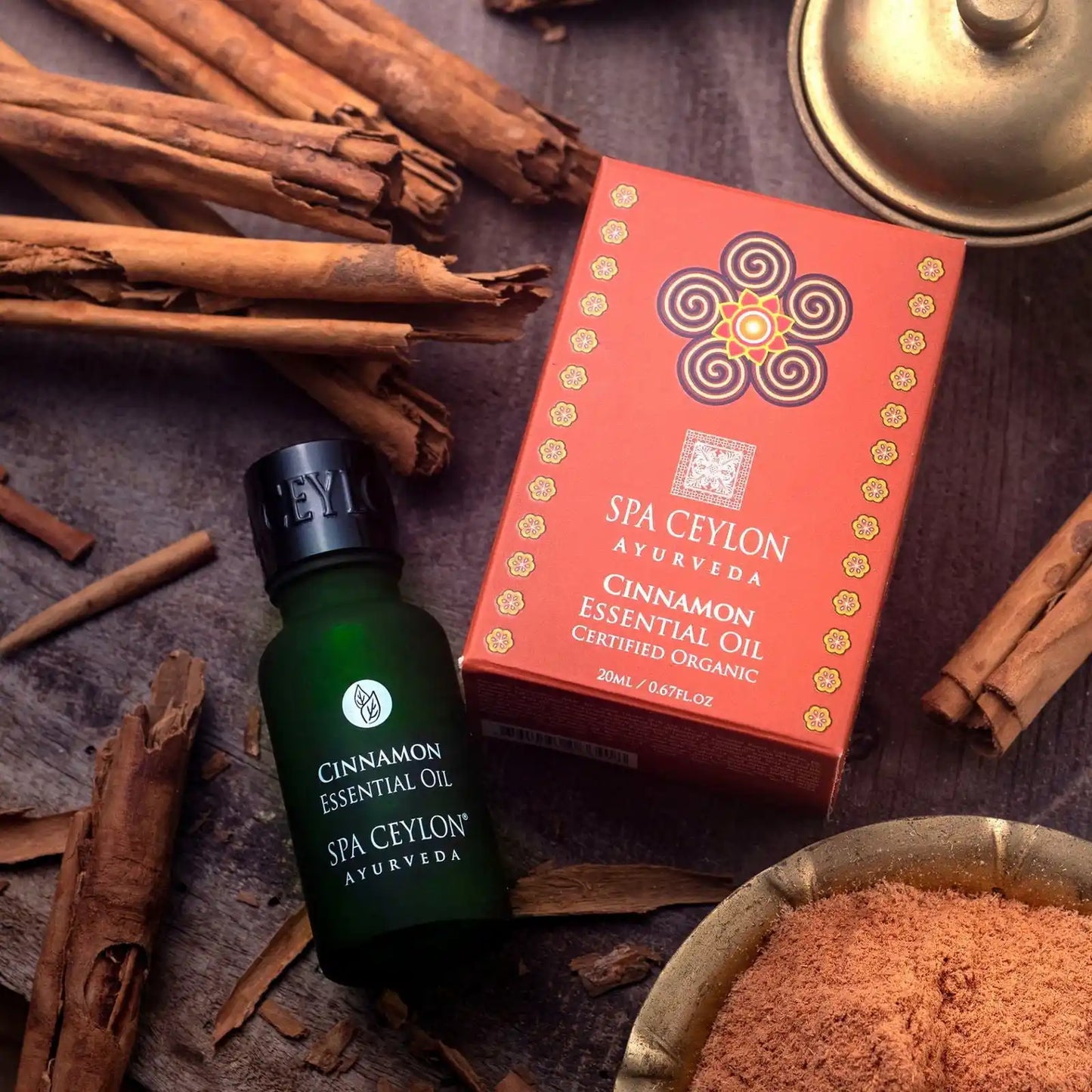 Cinnamon essential oil bottle and box with cinnamon sticks and powder on wooden surface