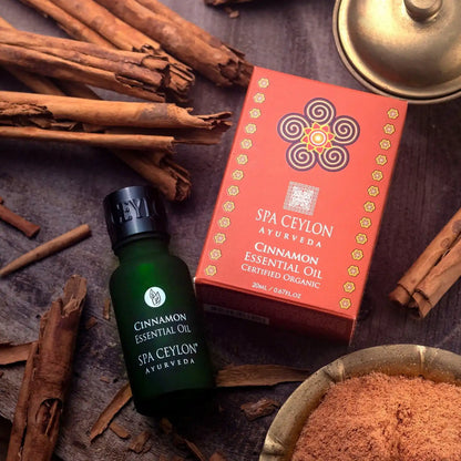 Cinnamon essential oil bottle and box with cinnamon sticks and powder on wooden surface