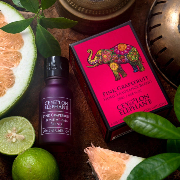 Pink Grapefruit home aroma blend bottle and box with citrus fruits and leaves on a wooden surface.